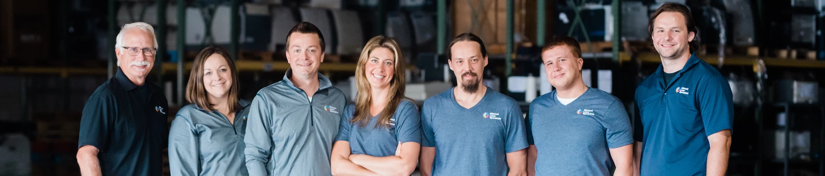 A group of employees at Midwest Laser Specialists posing for a picture in a warehouse